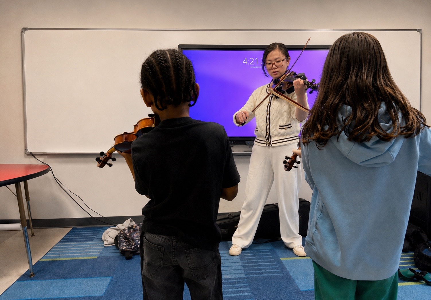 Yulong Han demonstrating violin technique for students in a classroom